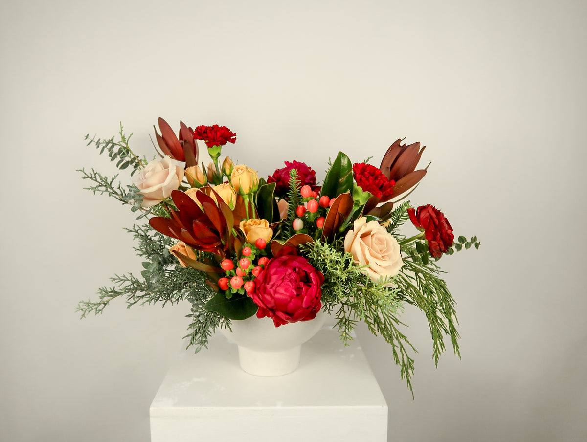 Colorful flower arrangement in a white vase on a light gray background