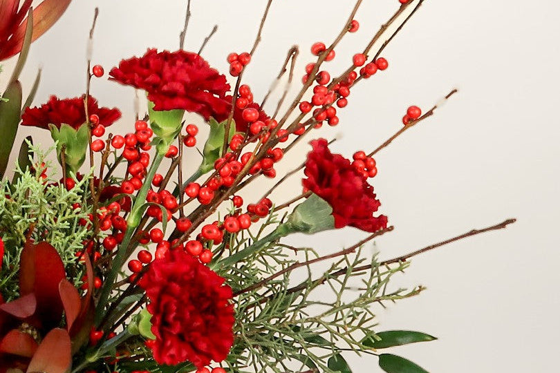 Floral arrangement with red flowers and berries on a light background