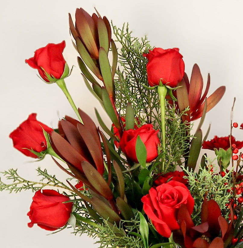Bouquet of red roses with greenery on a light background